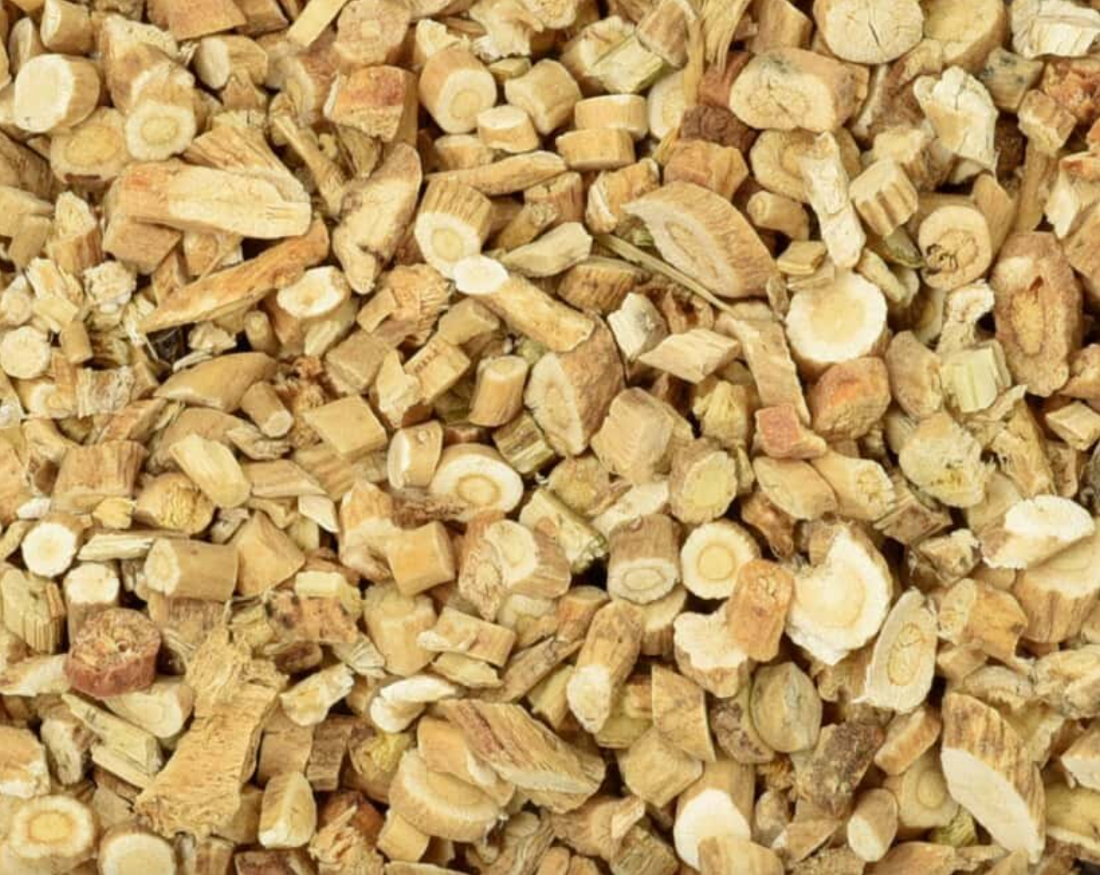 Close-up texture of dried astragalus root pieces, showing small beige pieces used for teas and herbal remedies.