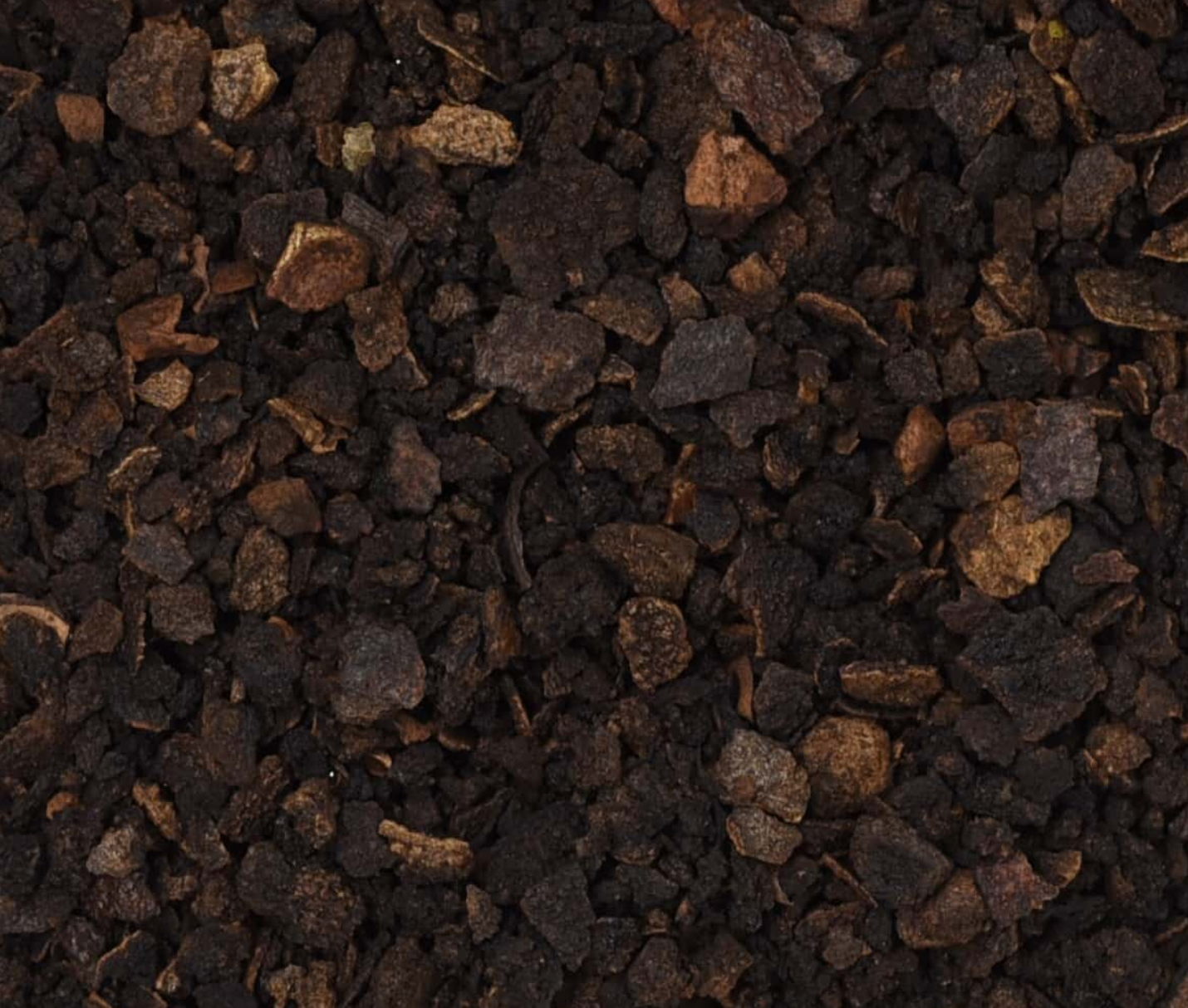 Close-up texture of dried black walnut hulls, showing dark brown hull pieces used for teas and herbal remedies.