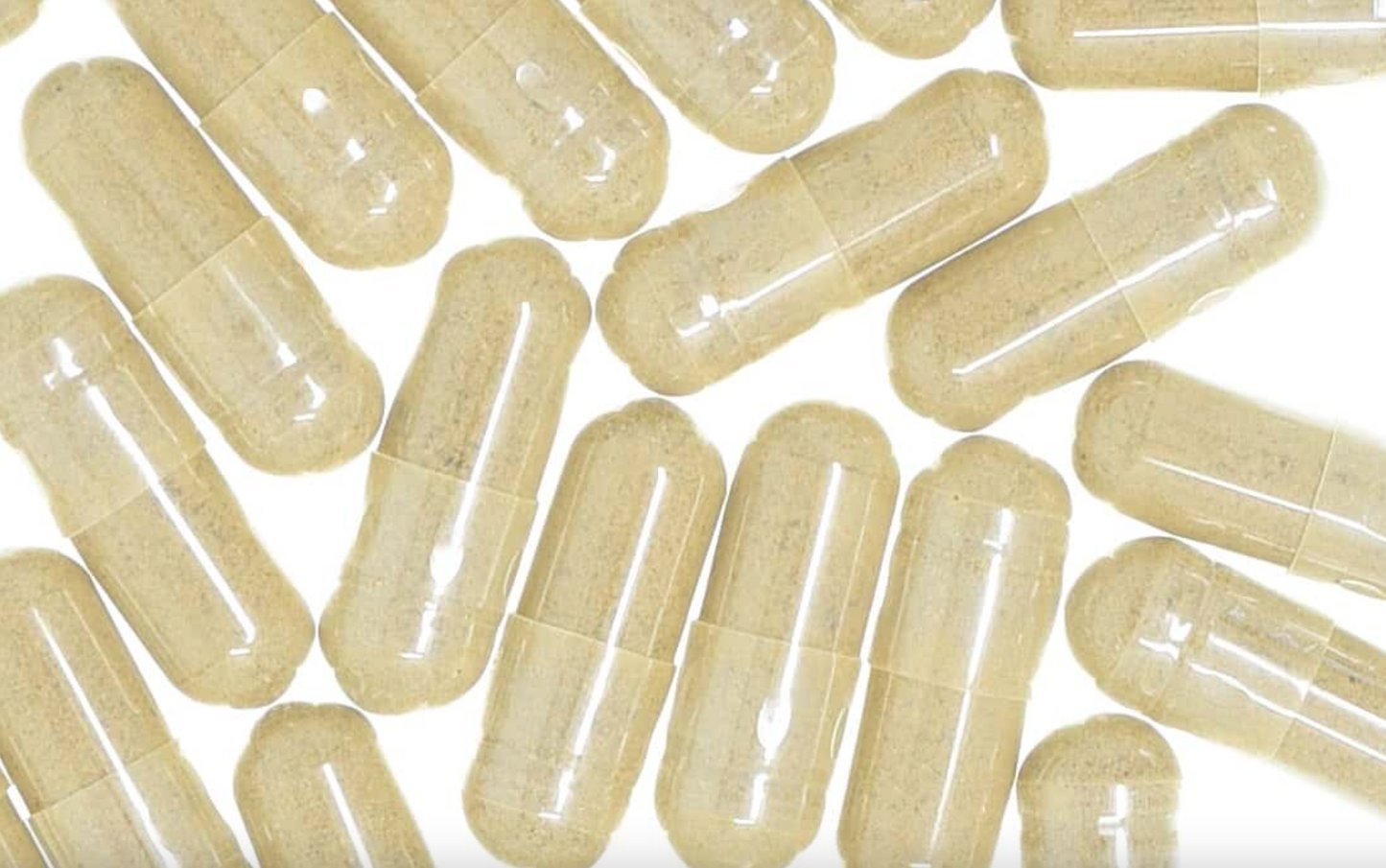 Burdock root capsules with clear glossy shells, filled with beige powder, used for natural health and wellness.