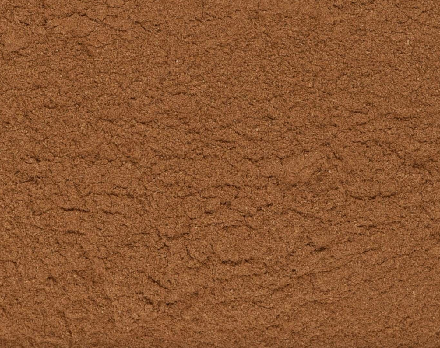 Close-up texture of dried cinnamon powder, showing brown powder used for teas and herbal remedies.