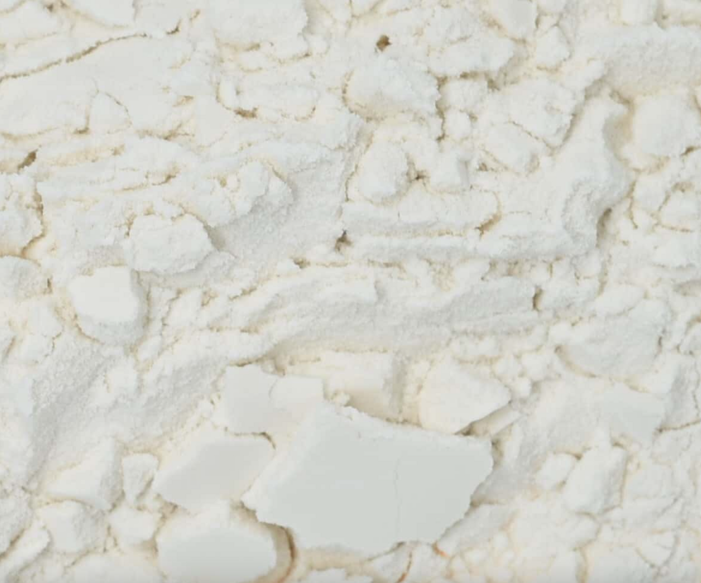 Close-up texture of dried gum arabic/acacia gum powder, showing fine white powder.