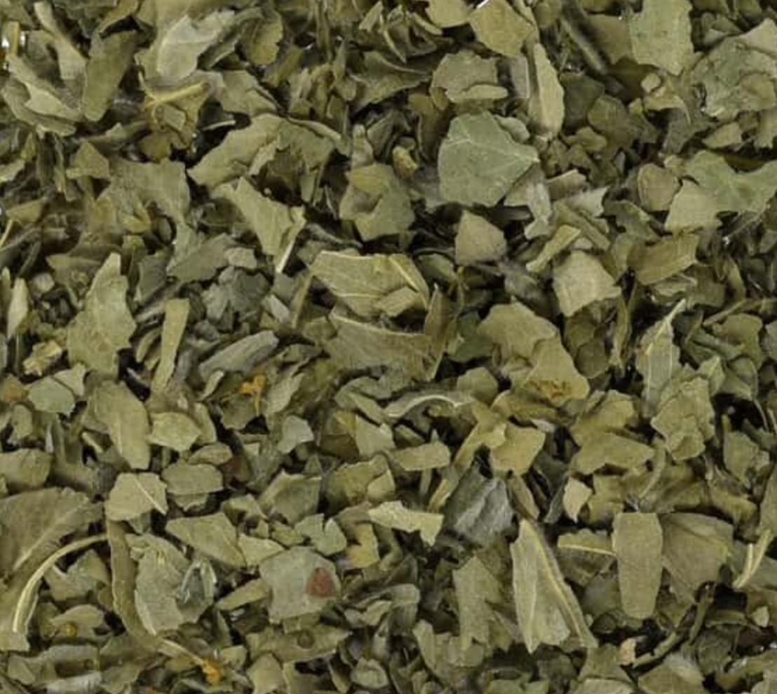 Close-up of dried lady's mantle herb, showing chopped green leaves used for teas and herbal remedies.