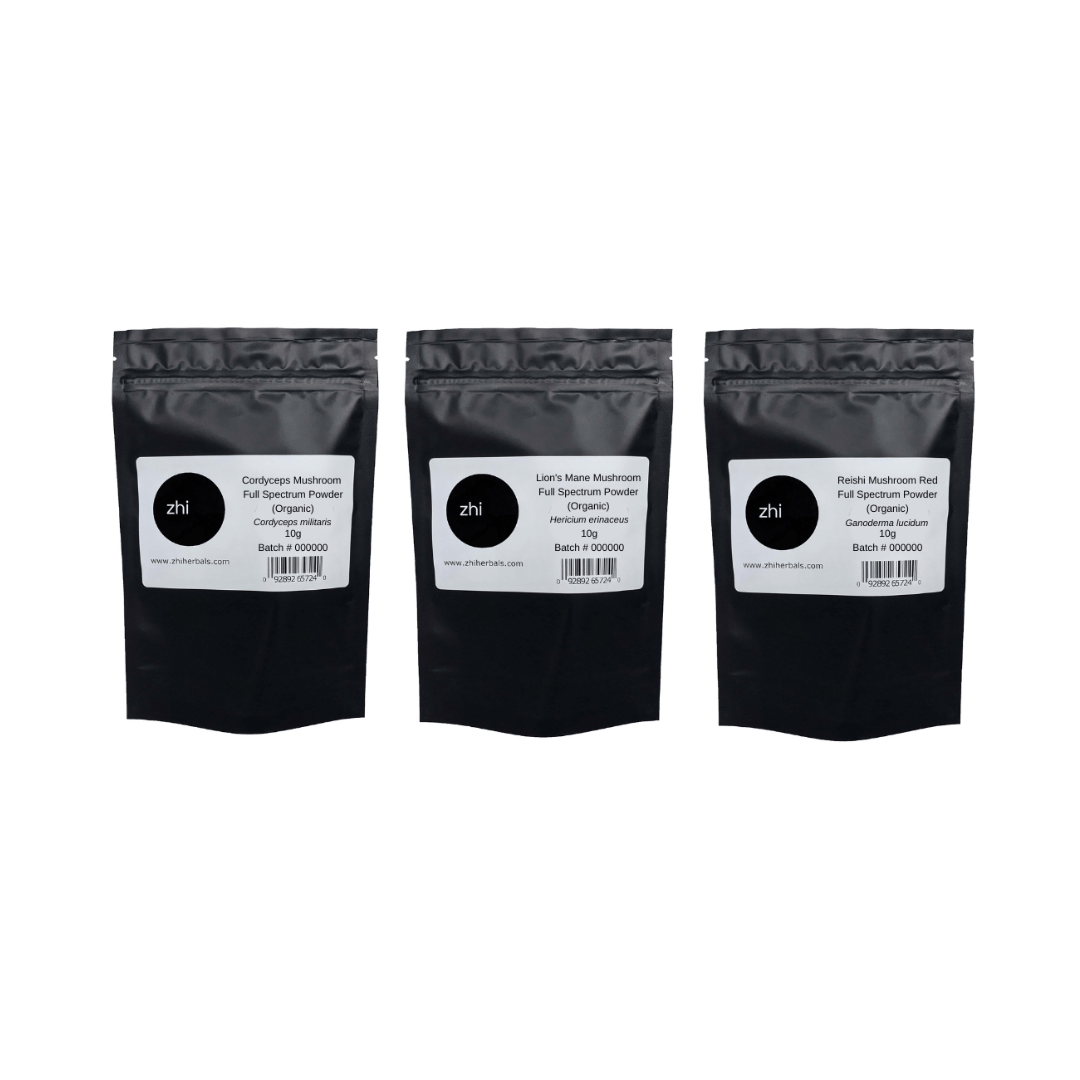 A row of three Zhi Herbals mushroom powders (Organic) in black resealable bags with product labels and barcodes.