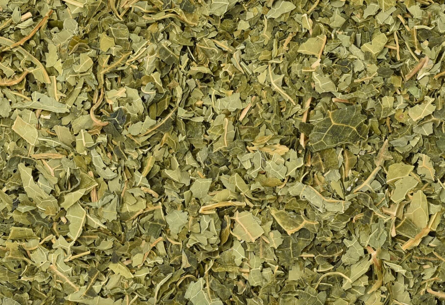 Close-up of dried papaya leaf, showing chopped green leaves used for teas and herbal remedies.