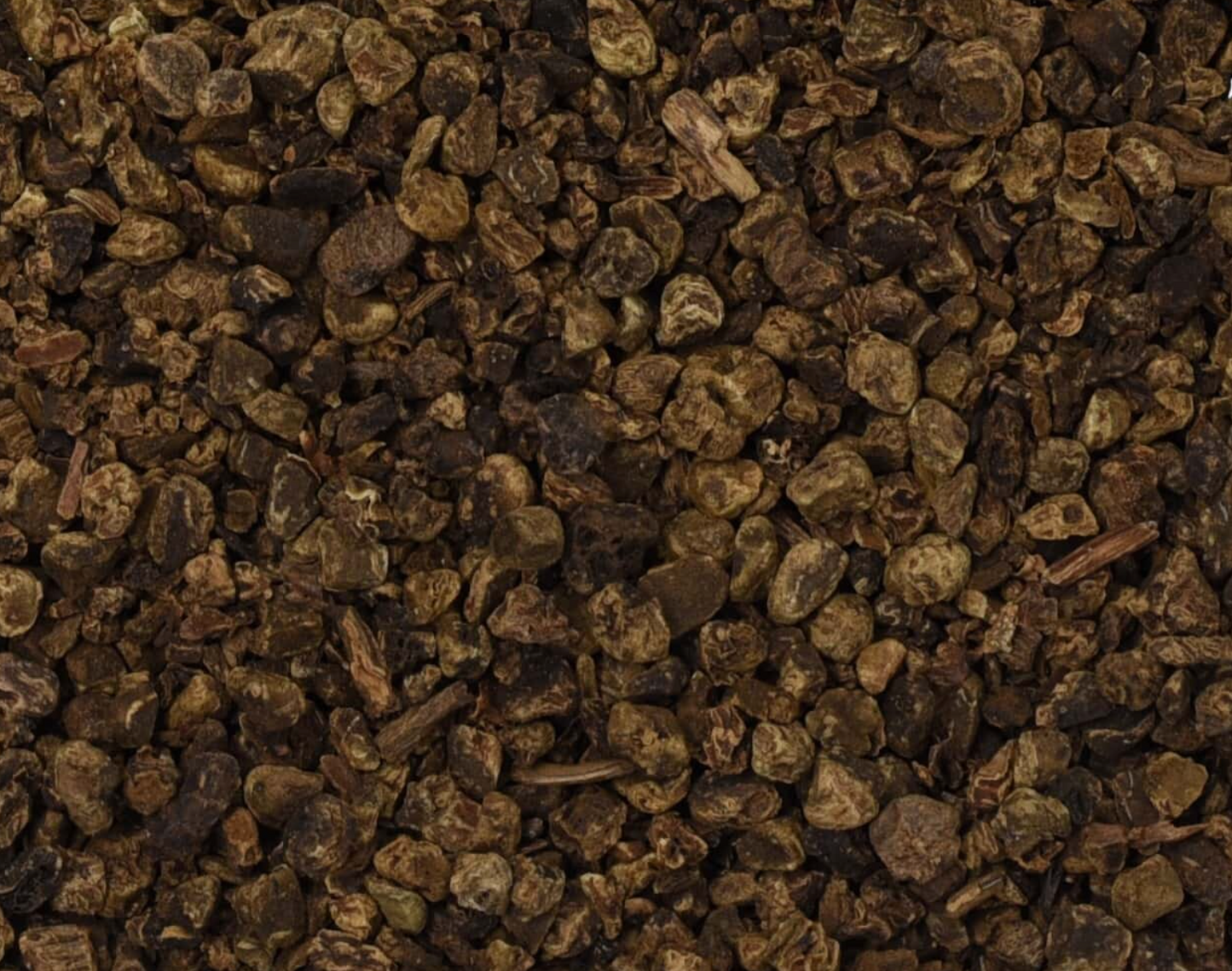 Close-up of dried valerian root, showing small dark brown chopped root pieces used for teas and herbal remedies.